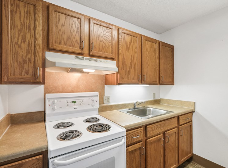 residential kitchen at Sundale Manor Apartments with white appliances and wood cabinetry